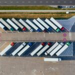 EU approves new sustainable supply chain rules An arial view looks down on parked transporter trucks.