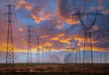 Market-wide Half-Hourly Settlement: Fundamental change to the UK electricity market A row of electricity pylons in front of a setting sun, potentially to be impacted by Market-wide Half-hourly settlements