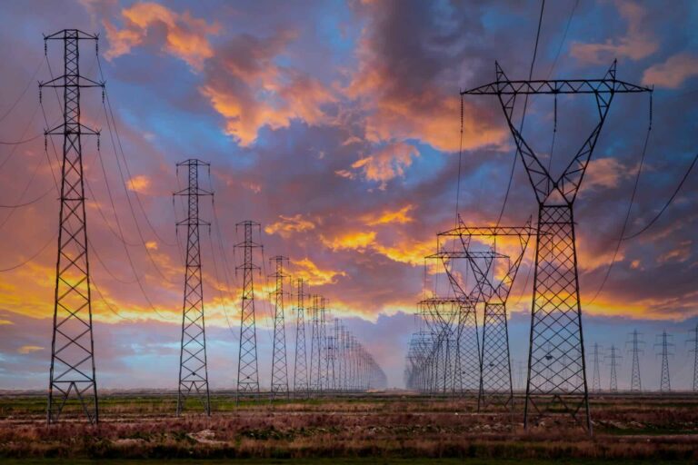 A row of electricity pylons in front of a setting sun, potentially to be impacted by Market-wide Half-hourly settlements