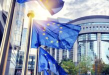Green Claims Directive: EU Council adopts its position on greenwashing The EU flag waves in the wind outside of a large office building