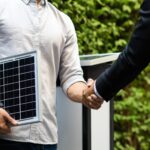 Labour’s first month: Key energy sector changes so far Two men in semi-professional attire shake hands, while one is holding a small sample of solar panel technology