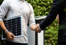 Labour’s first month: Key energy sector changes so far Two men in semi-professional attire shake hands, while one is holding a small sample of solar panel technology