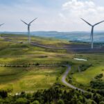 Strategic Innovation Fund to receive more funding for UK decarbonisation Wind turbines on the horizon stand above green hills in Wales