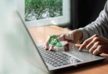 Understanding ESG: Environmental, Social, and Governance A man types on his computer, working on an ESG report. Symbols hover above his keyboard in a futuristic way, including symbols such as windmills and a CO2 cloud.