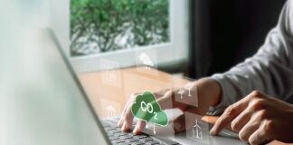 Understanding ESG: Environmental, Social, and Governance A man types on his computer, working on an ESG report. Symbols hover above his keyboard in a futuristic way, including symbols such as windmills and a CO2 cloud.