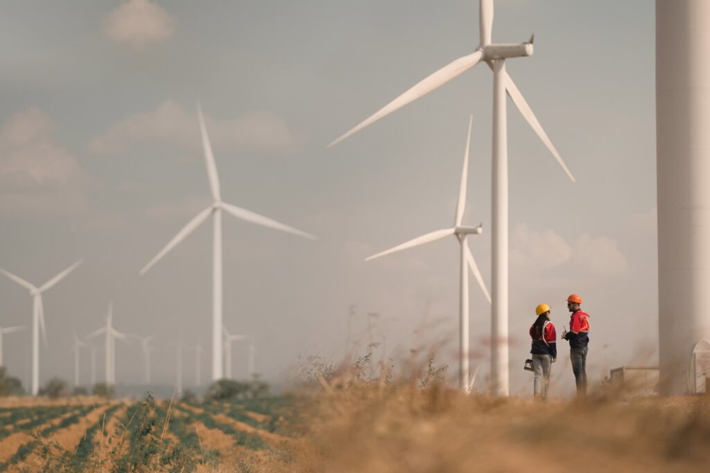 Two people stand in a wind farm field