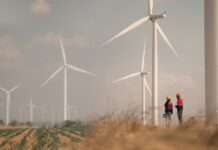 UK hits historic 30GW milestone of wind generation capacity Two people stand in a wind farm field