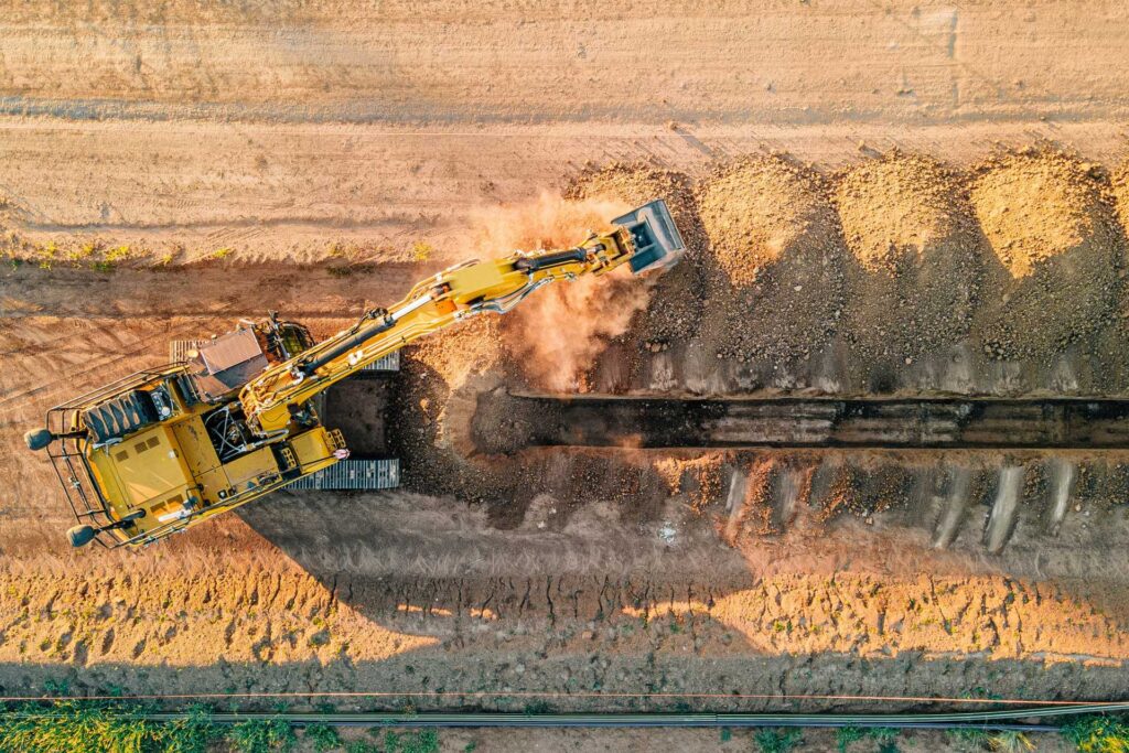 A tractor digs up a dirt road so that a pipeline can be put down.