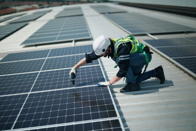 A man on the roof of a building installs solar panels.