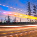 What’s next for the Demand Flexibility Service? Car lights blur in front of power lines as the sun sets in the distance.