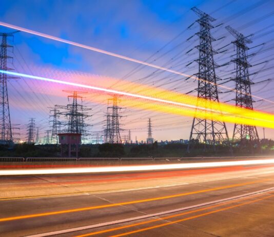 What’s next for the Demand Flexibility Service? Car lights blur in front of power lines as the sun sets in the distance.