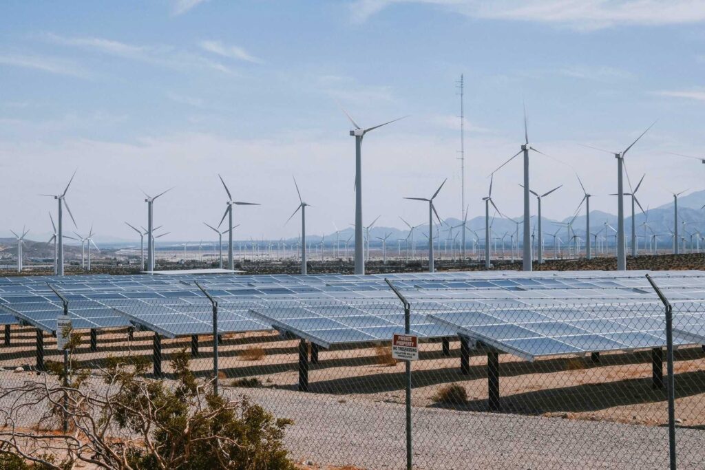 Wind turbines stand behind sun panels in a dry area of land. The UK launched its Global Clean Power Alliance at the G20 Summit