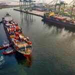 UK government sets six principles for voluntary carbon and nature market integrity Three small tugboats guide a large cargo ship to the dock