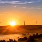 Government unveils Clean Power Action Plan to achieve 2030 energy goals The sun sets on the horizon, outlining wind turbines on the crest of a hill