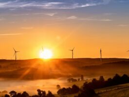 Government unveils Clean Power Action Plan to achieve 2030 energy goals The sun sets on the horizon, outlining wind turbines on the crest of a hill