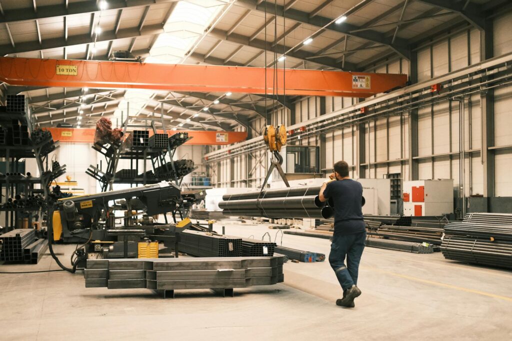 A man works in a manufacturing warehouse moving steel.