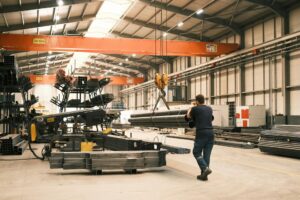 A man works in a manufacturing warehouse moving steel.