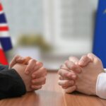 Business Insider: Corporate Sustainability Due Diligence Directive (CSDDD) Two people sitting at a table in front of a UK and EU flag