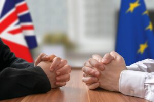 Two people sitting at a table in front of a UK and EU flag