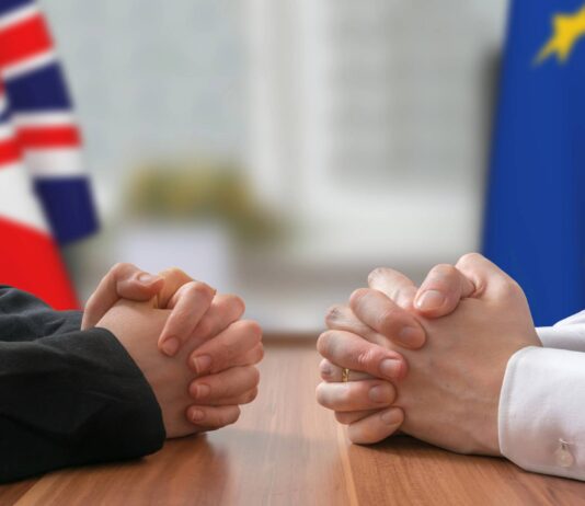 Business Insider: Corporate Sustainability Due Diligence Directive (CSDDD) Two people sitting at a table in front of a UK and EU flag