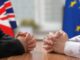Business Insider: Corporate Sustainability Due Diligence Directive (CSDDD) Two people sitting at a table in front of a UK and EU flag