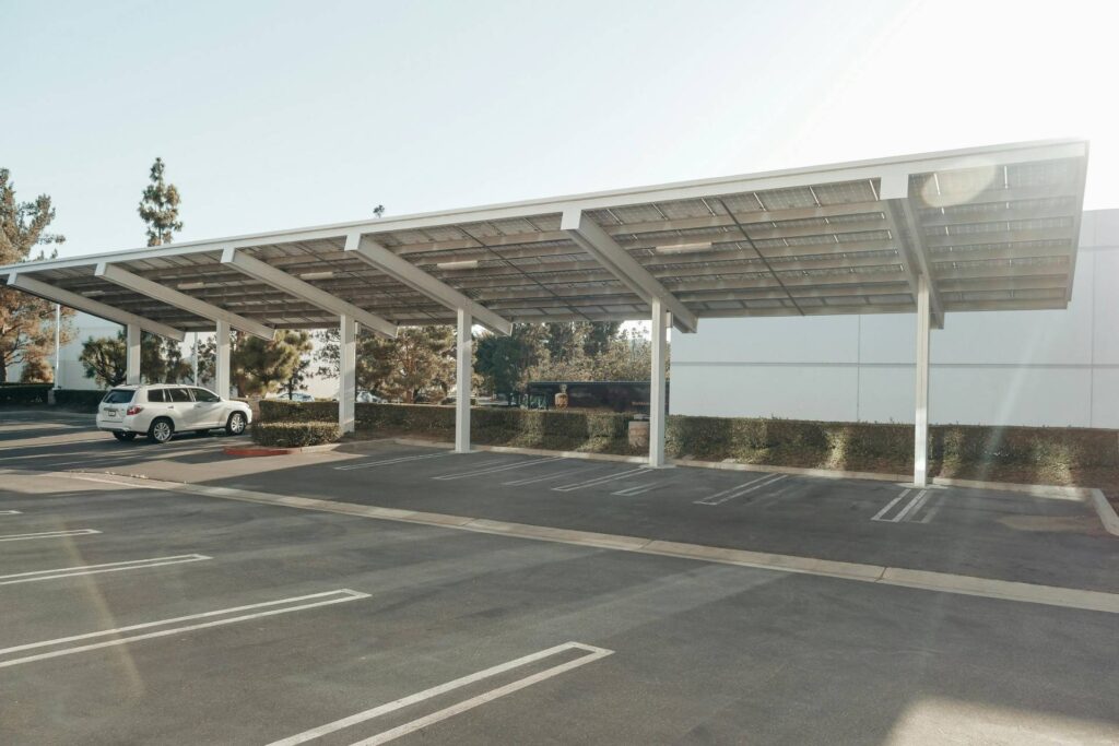 A white car sits under a solar carport on a sunny day.