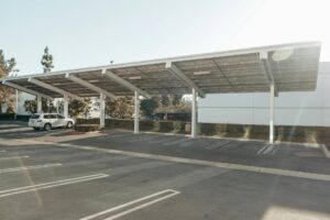 A white car sits under a solar carport on a sunny day.