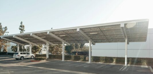 A white car sits under a solar carport on a sunny day.