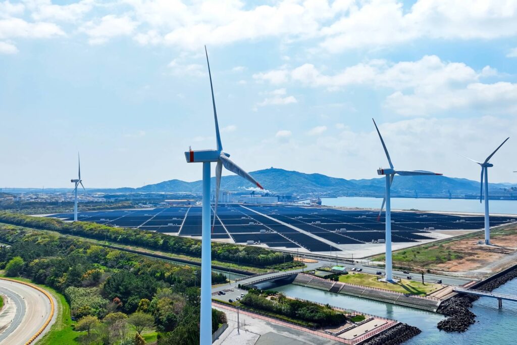 Aerial view of a hybrid power plant with wind turbines and solar panels