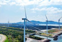 Aerial view of a hybrid power plant with wind turbines and solar panels