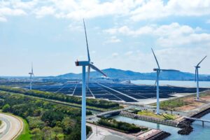 Aerial view of a hybrid power plant with wind turbines and solar panels