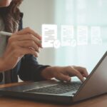 ESOS: New template for Progress Update submissions A woman sits at her laptop typing, with images of her screen projected in front of her
