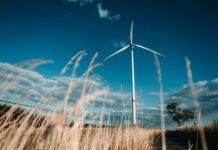UK government reforms CfD Scheme to accelerate renewable energy rollout A wind turbine on a field with blue sky behind it.