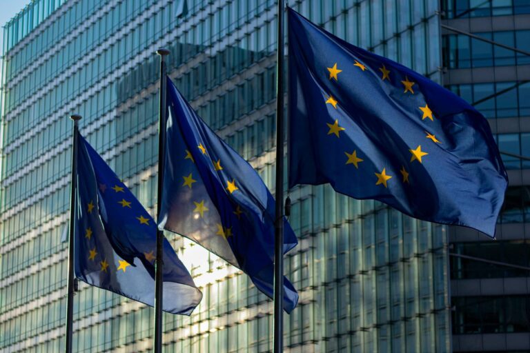 Three European flags hanging on poles