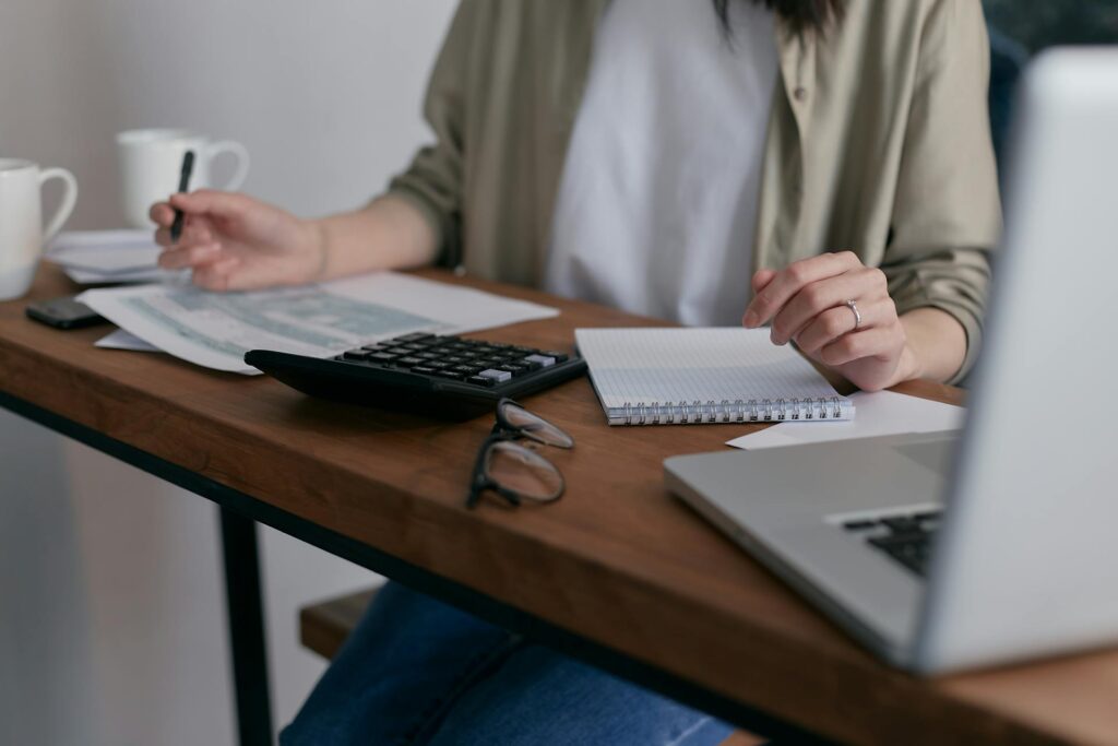 A woman sits at a desk working on her laptop.