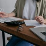 EU delays sustainability reporting requirements for large companies A woman sits at a desk working on her laptop.