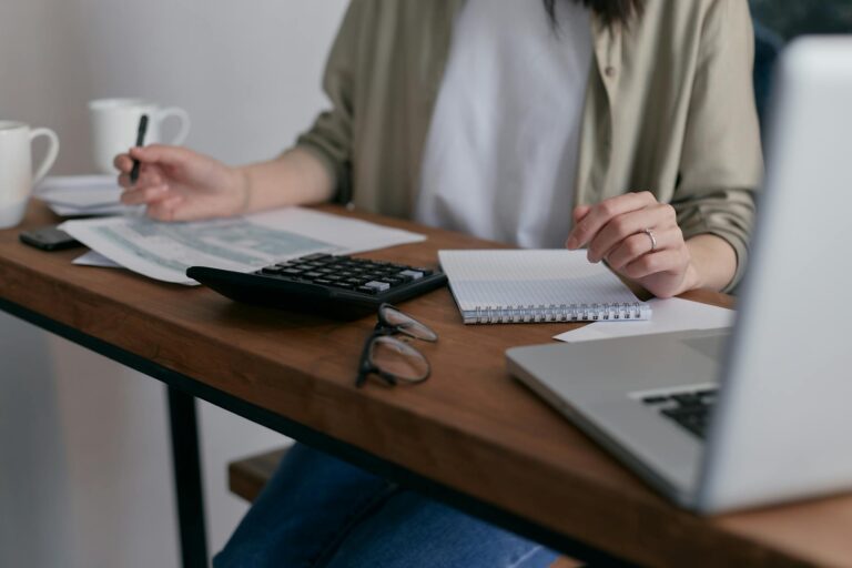 A woman sits at a desk working on her laptop.