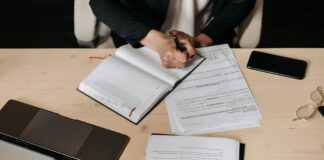 Consultation: government seeks views on UK Sustainability Reporting Standards Professional person writing in a journal on a desk. A laptop and other shets of paper are also on the desk.