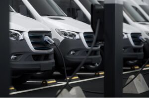 A row of commercial electric vans are charging