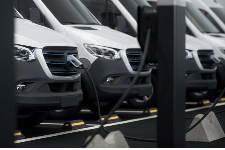 A row of commercial electric vans are charging