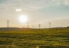 ISO and GHG Protocol announce partnership to harmonise carbon accounting standards Blue sky, green grass and wind turbines