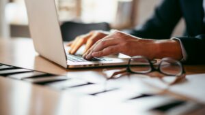 A view of a desk with a man in a suit working on a laptop